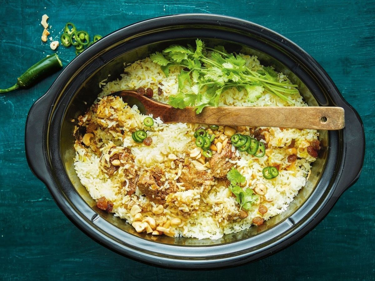 Rindfleisch-Biryani mit Reis, Kräutern und frischem Koriander, serviert in einem großen Slow Cooker.