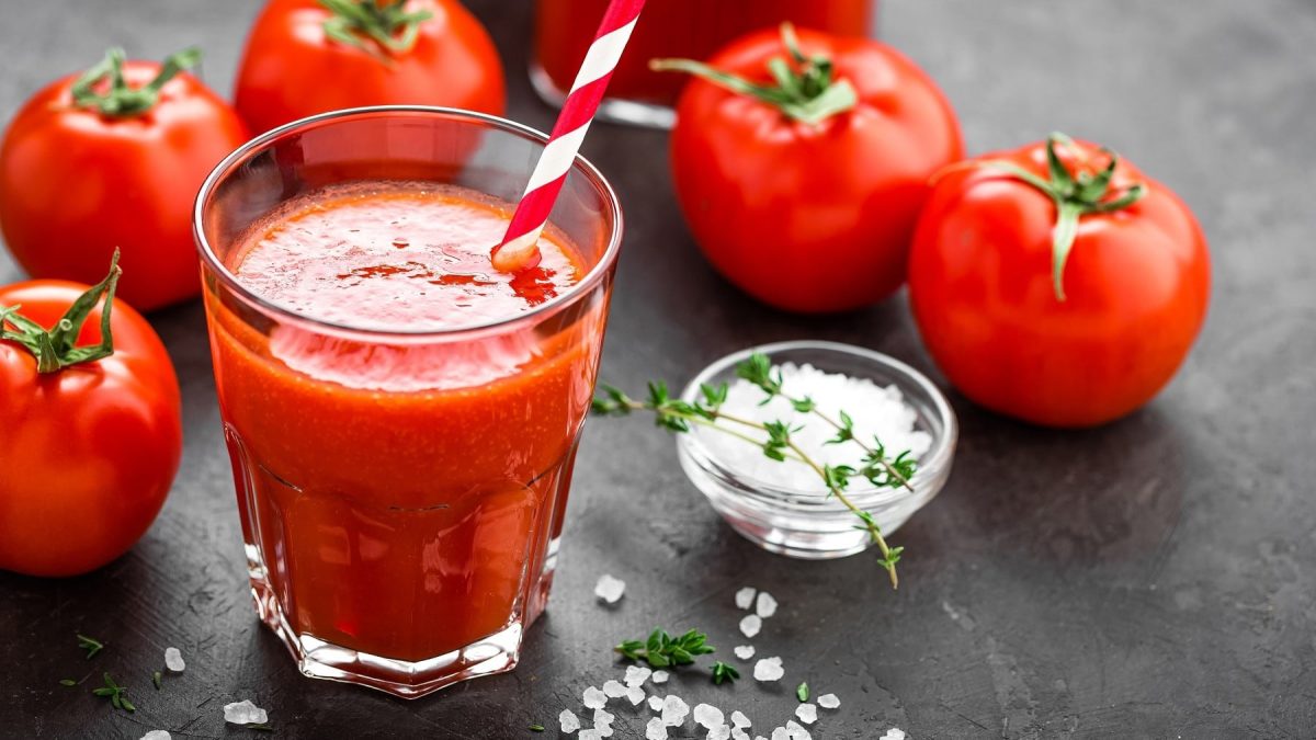 Tomatensaft selbst machen und in Gläser abfüllen, serviert mit Salz und Pfeffer auf einer Steinplatte.
