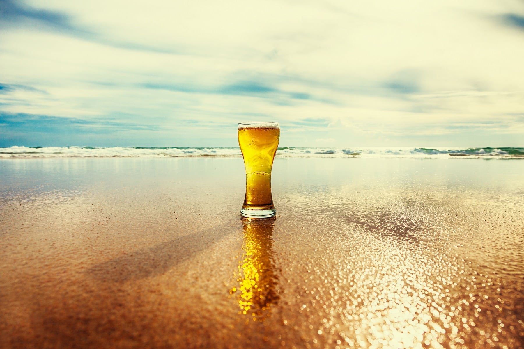 Ein Glas Bier steht am Strand