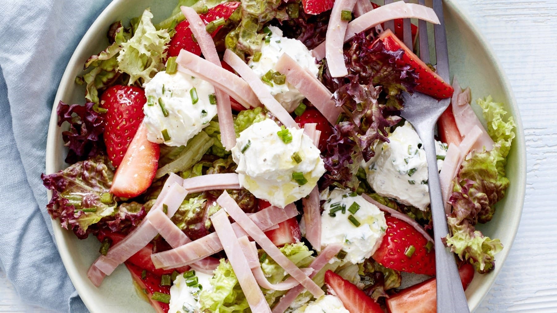Erdbeersalat mit Frischkäse und Schinken, zusammengestellt in einer Salatbowl und garniert mit Schnittlauch und einer leichten Vinaigrette.