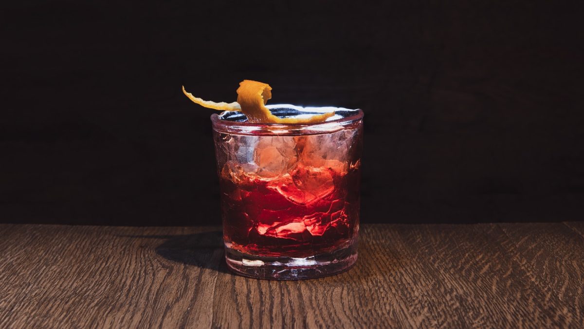 Der Boulevardier Cocktail auf einem Holztisch mit dunklem Hintergrund.