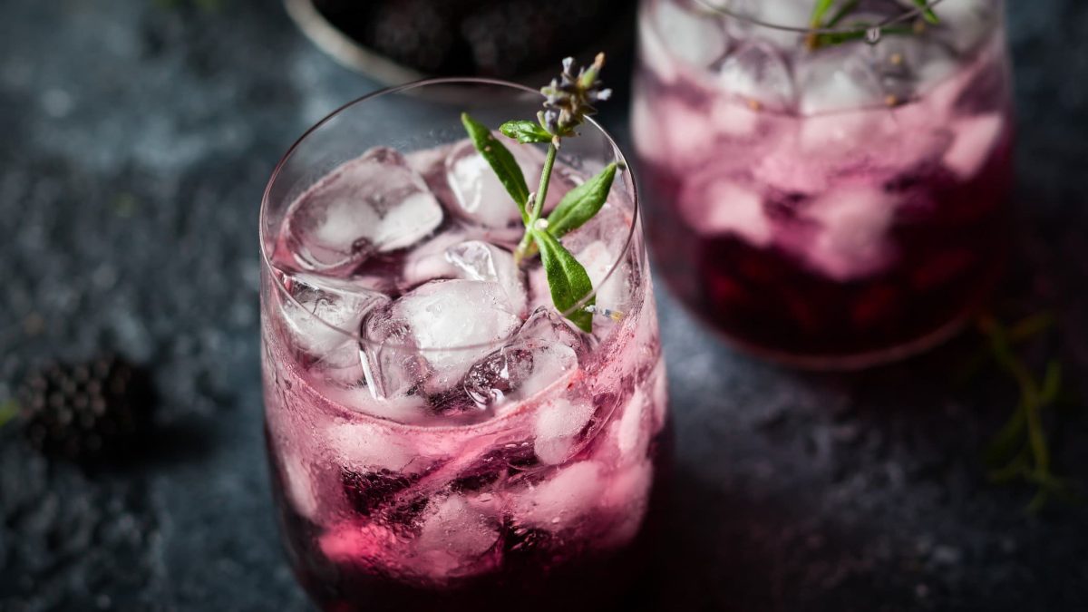 Zwei Gläser mit dem violetten Cocktail auf einem dunklen Untergrund.