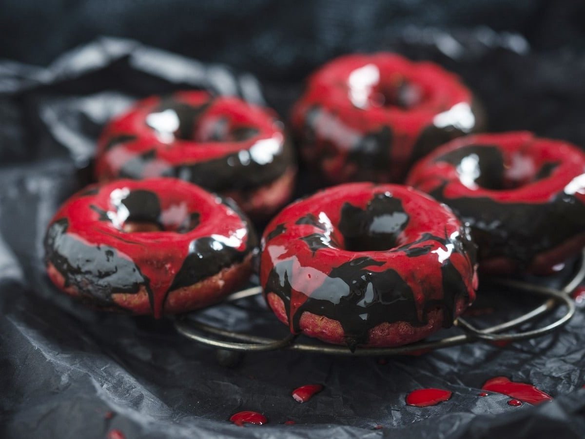 Auf einem schwarzen Teller liegen Rote-Bete-Donuts mit Schokoladenglasur. Sie sind mit roter und schwarzer Glasur überzogen.