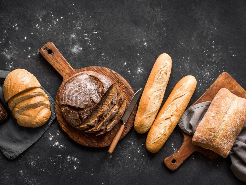 Verschiedene Brotsorten zum Tag des Brotes auf schwarzem Hintergrund