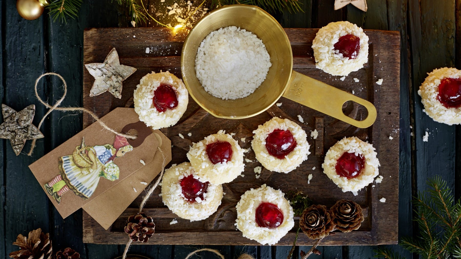 Rotkäppchen-Kekse mit Kokosraspeln und Puderzucker verziert, serviert auf einem Holzbrett mit allerlei weihnachtlicher Dekoration.