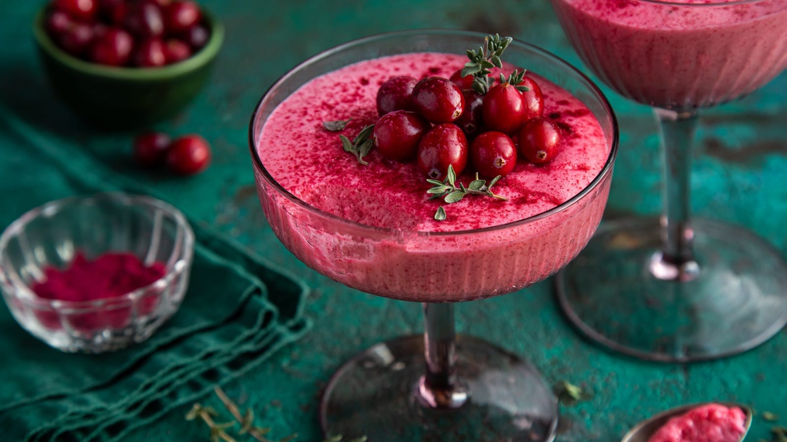 Ein Glas mit Cranberry-Mousse auf einem grünen Tisch.