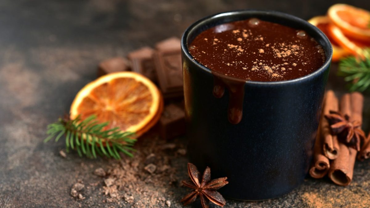 Eine schwarze Tasse heiße Orangenschokolade auf einem Holztisch.