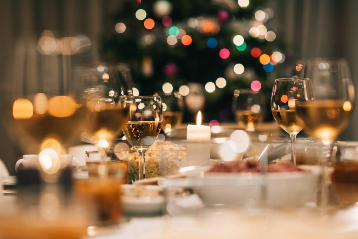 Vorspeisen zum Weihnachtsdinner gedeckter Tisch mit gefüllten Gläsern.Im Hintergrund Weihnachtsbaum. Frontalaufnahme.