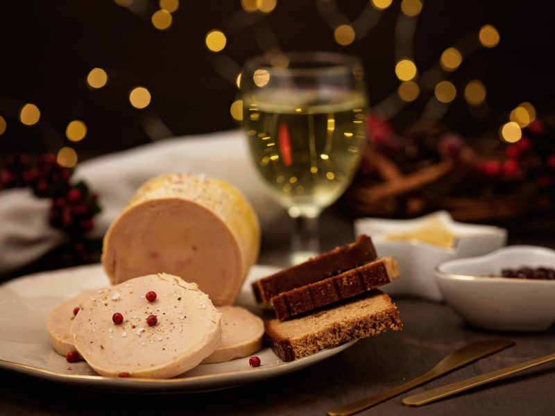 Weihnachtsessen in Frankreich, ein gedeckter Tisch mit einem Weinglas und Foie Gras und weiteren Kleinigkeiten.