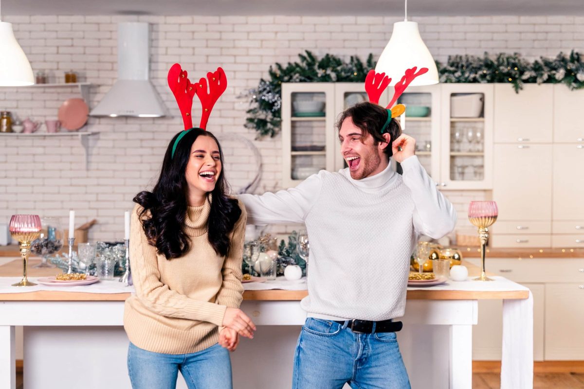Ein junges Paar, das zu Weihnachtsliedern in der Küche tanzt.
