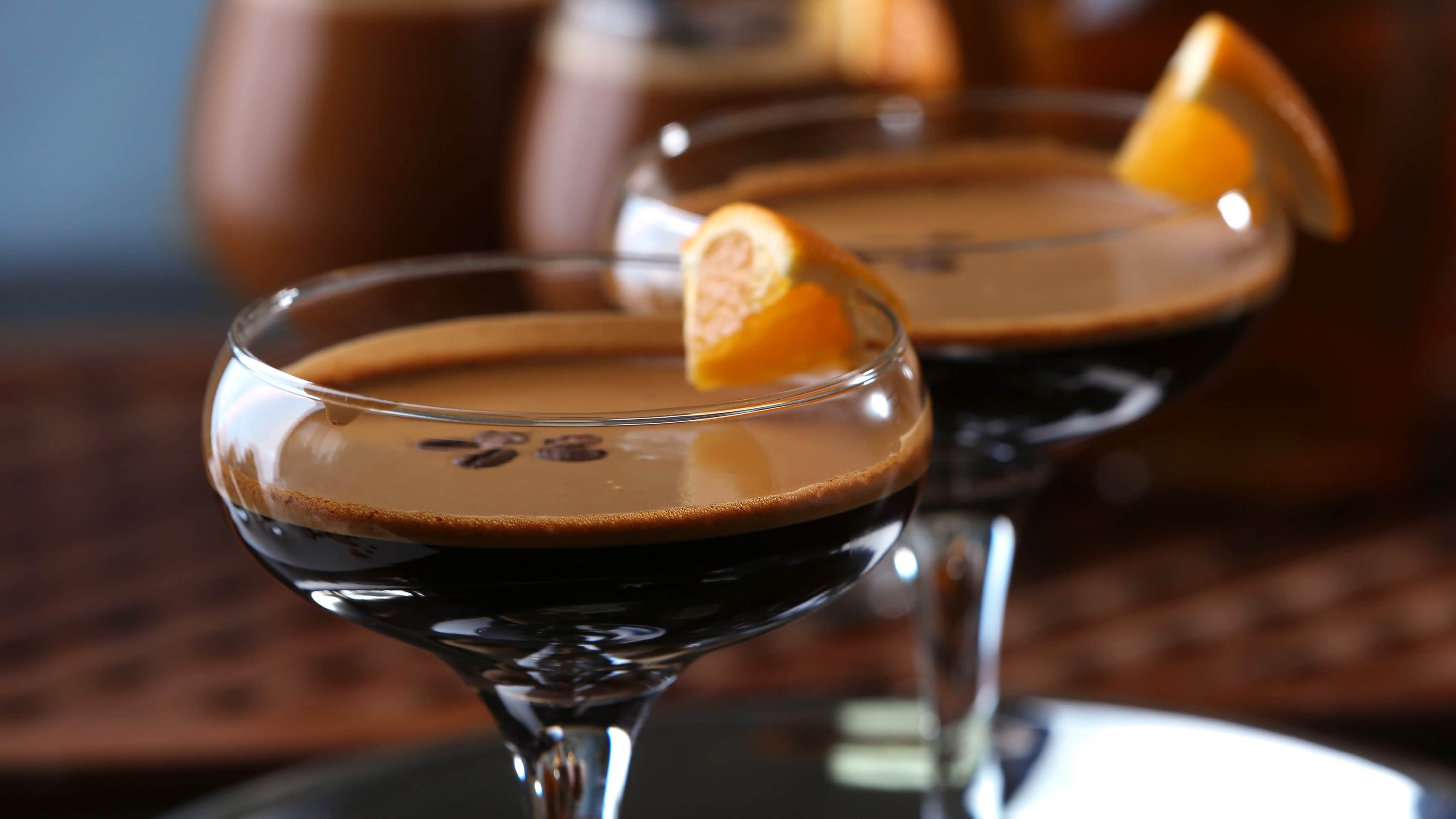Zwei Chocolate Orange Espresso Martini in Martinigläsern mit Garnitur auf dunklem Untergrund. Frontalansicht.