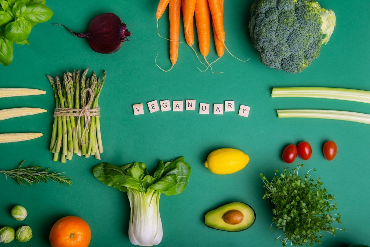 Veganuary 2023: Das Wort "Veganuary" mit Scrabble-Buchstaben gelegt, drumherum Gemüse angeordnet, alles Draufsicht.