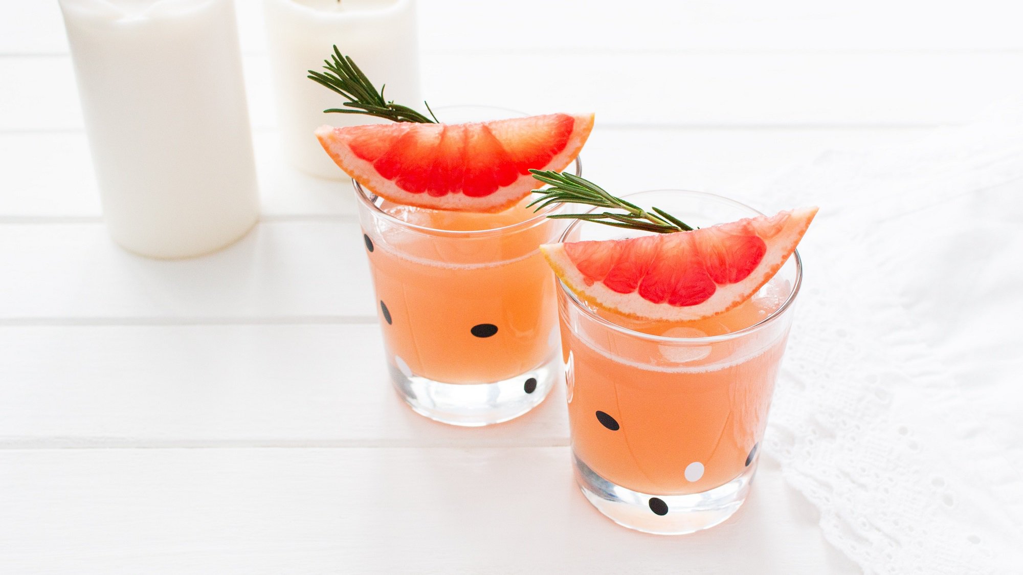 Zwei Shot-Gläser Grapefruit-Sirup mit je einem Zwei Rosmarin und einer Grapefruit-Spalte.