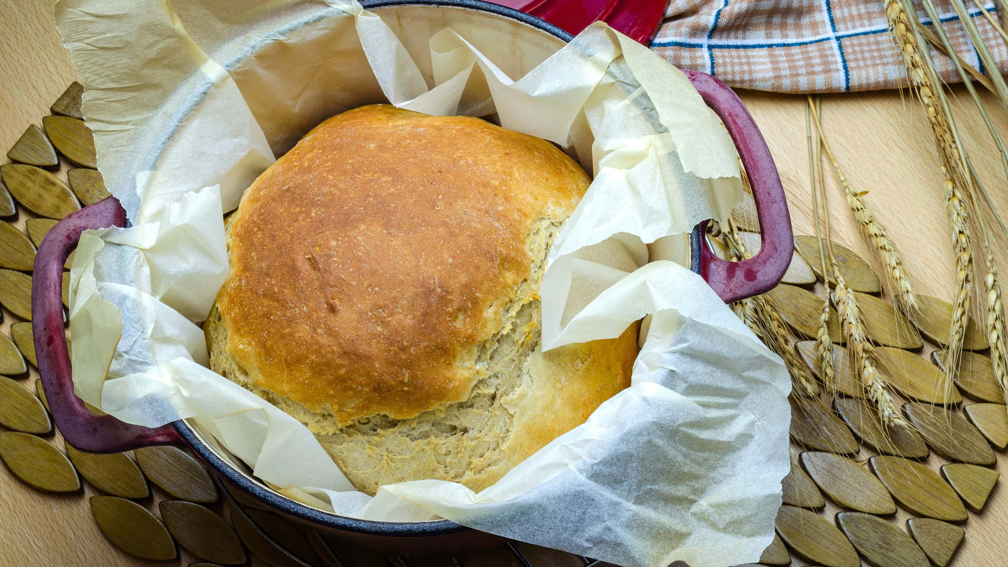 Crock-Pot Dinkel-Buttermilch-Brot ohne Hefe auf Tisch mit Ähren. Draufsicht.