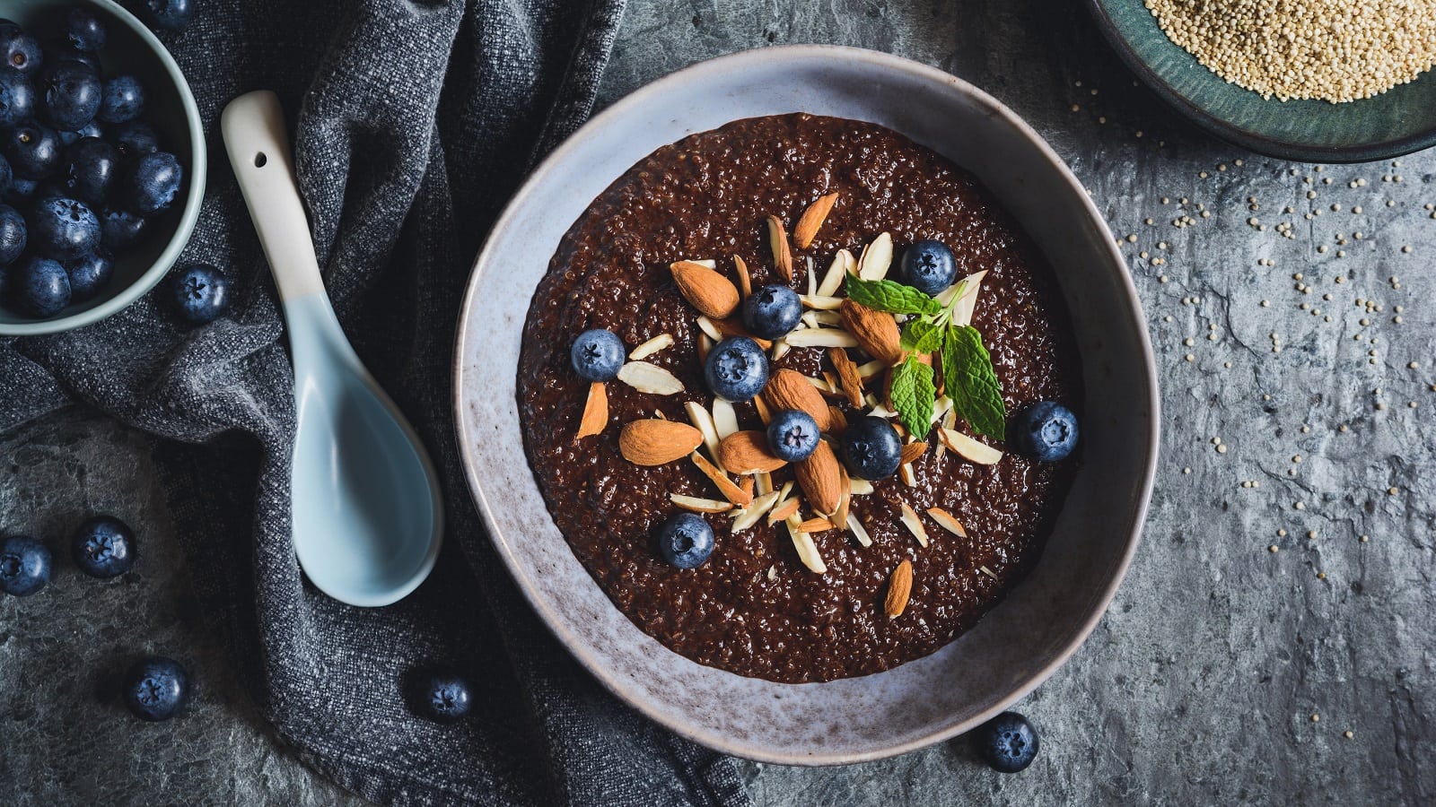 Eine Schüssel mit Kakao-Quinoa-Porridge auf grauem Tisch.