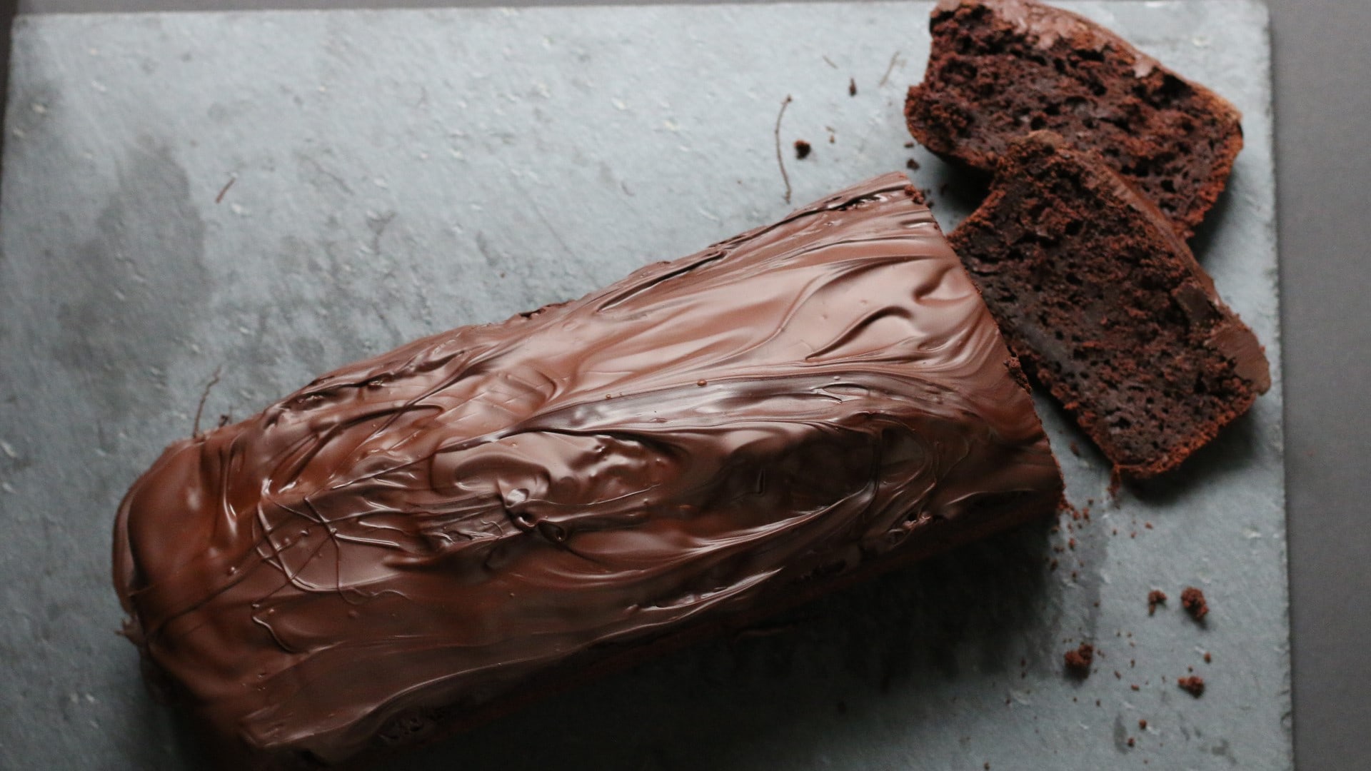 Schokoladenkuchen mit Schokoglasur auf grauem Untergrund.
