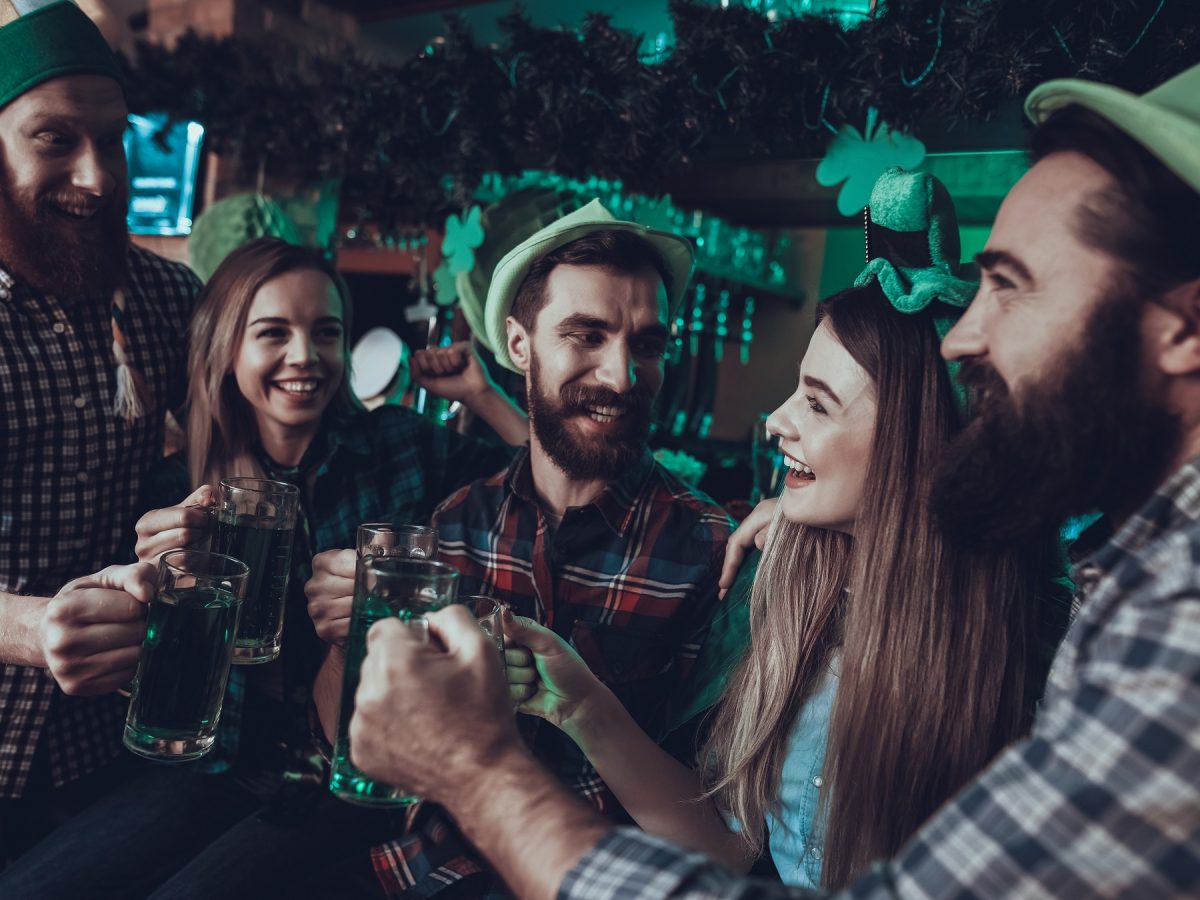 Freunde, die St. Patrick's Day in einer Bar feiern und mit grünem Bier anstoßen.