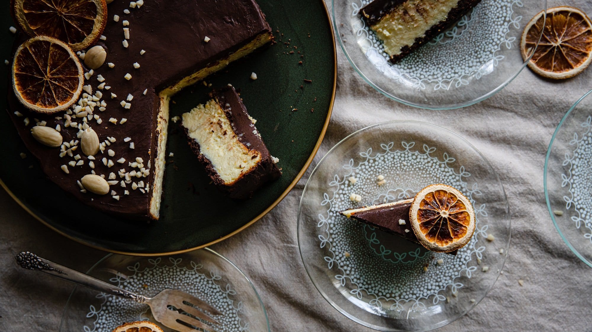 Ein angeschnittener ukrainischer Cheesecake, der auch als Lvivsky Syrnyk bekannt ist, in der Draufsicht, daneben zwei Teller mit je einem Kuchenstück.