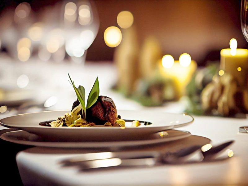 Michelin-Guide 2023: Ein stilvoll gedeckter Tisch mit Kerzen, Weingläsern und einem Teller mit einer Vorspeise.