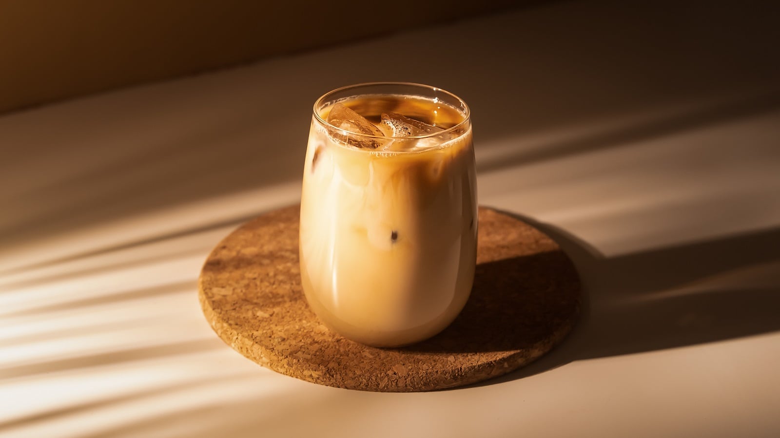Ein Glas Iced Tahini Latte vor einem braunen Hintergrund.