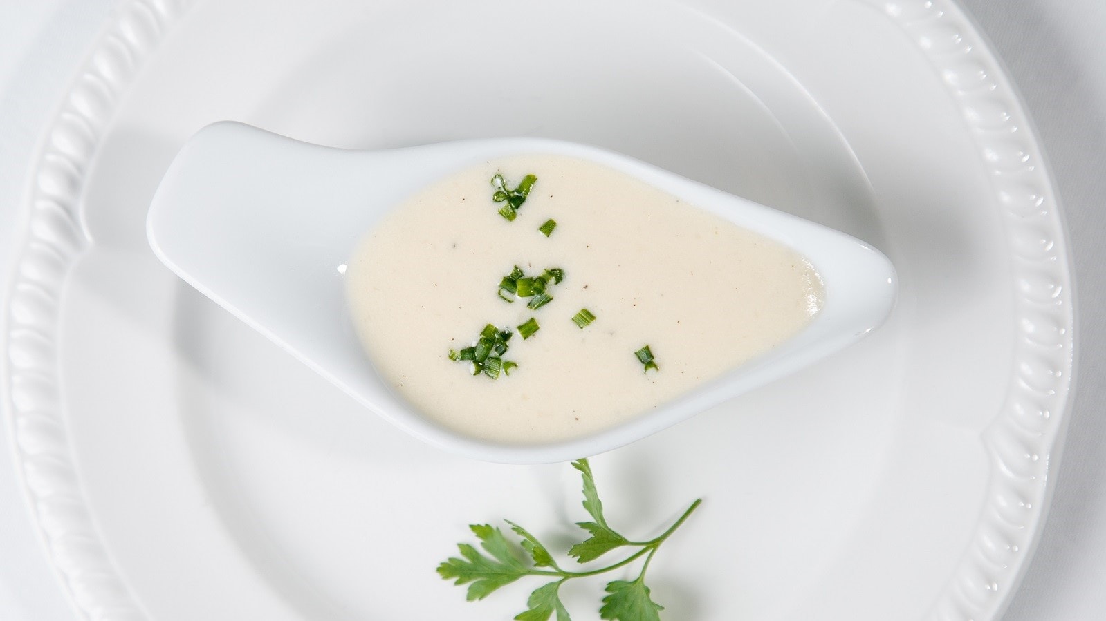 Eine Schale mit Beurre blanc auf einem weißen Teller.