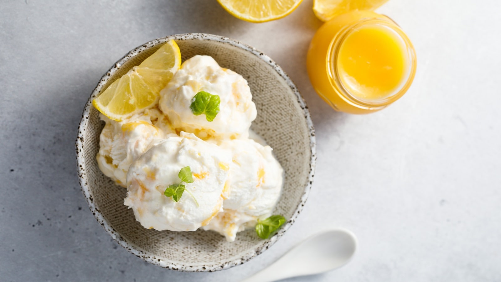 Ein Becher mit Lemon Curd Eis auf einem weißen Tisch.