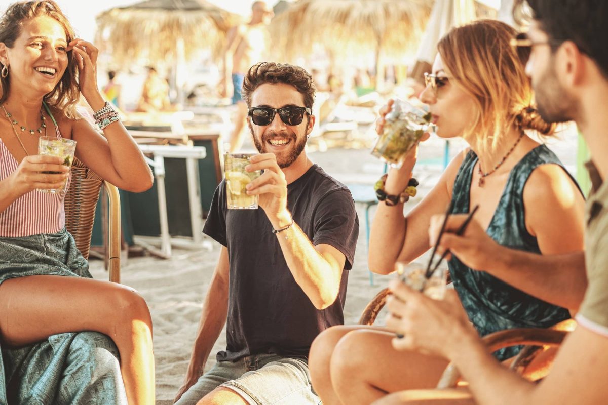 Strandbars in Berlin: Eine Gruppe von 4 Freunden sitzt mit Getränken in einer Strandbar