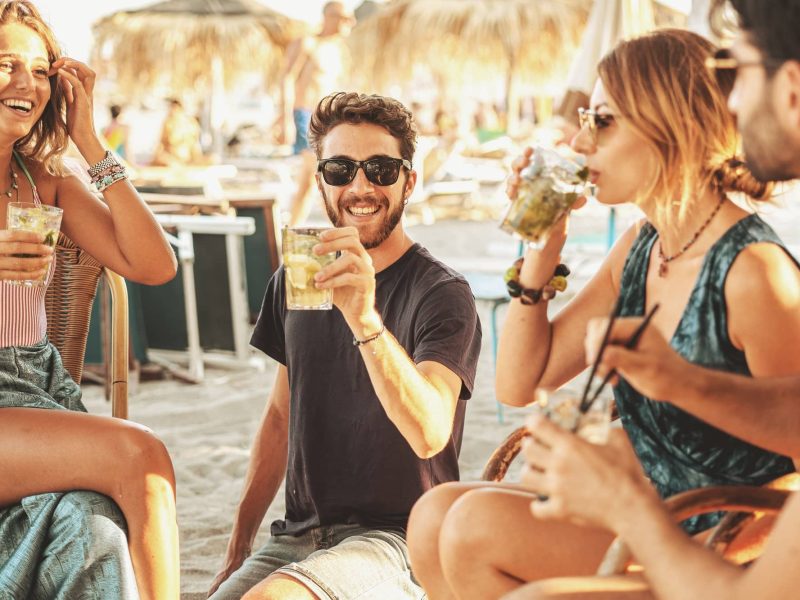 Strandbars in Berlin: Eine Gruppe von 4 Freunden sitzt mit Getränken in einer Strandbar