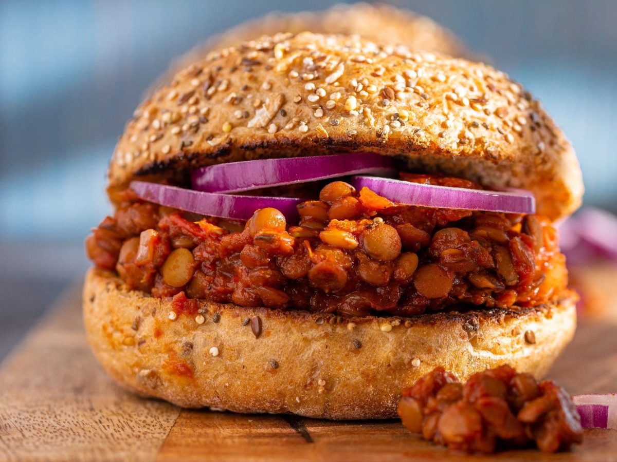 Ein veganer Sloppy Joes mit Linsen und roten Zwiebeln auf einem Brett.