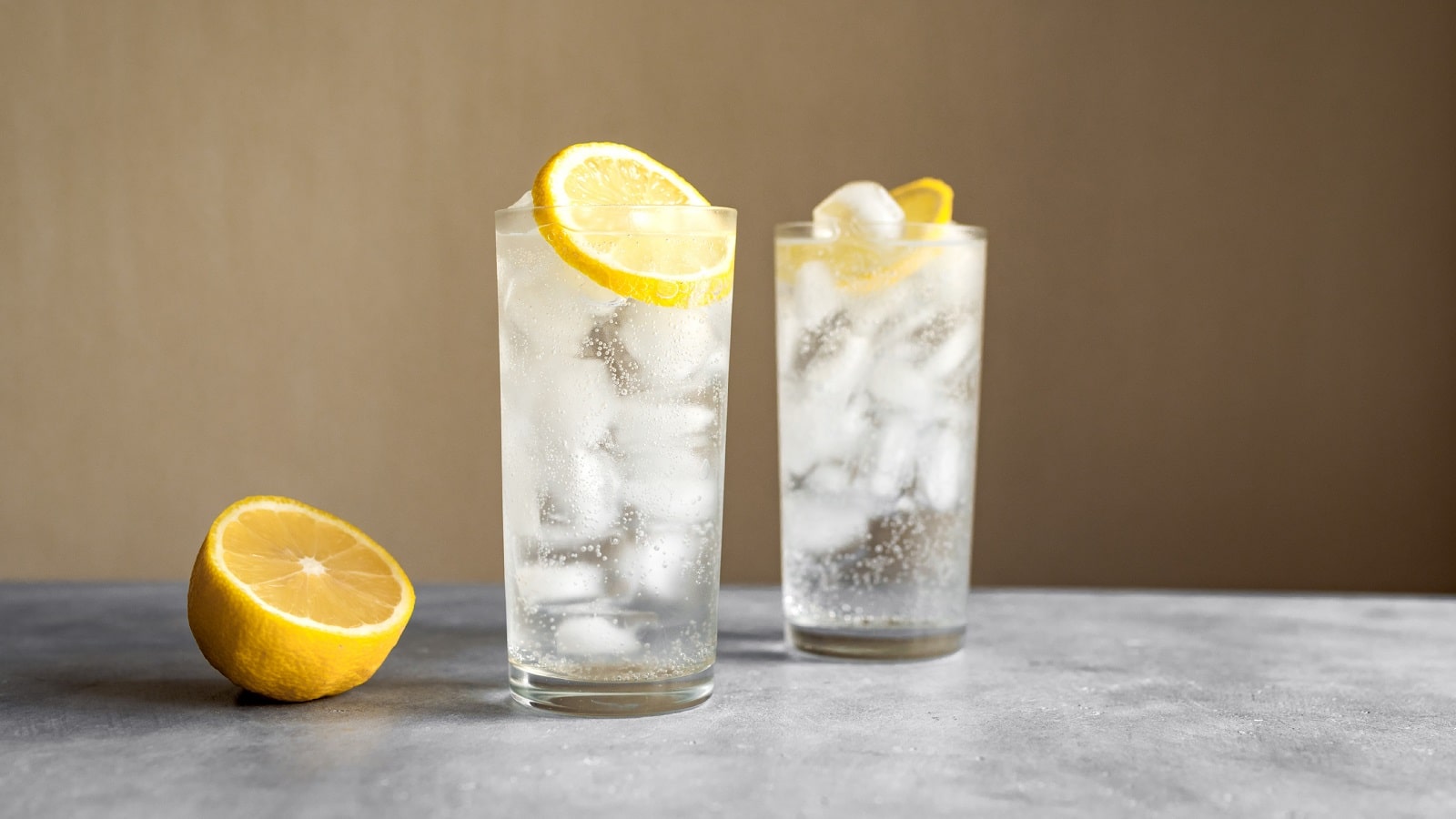 Zwei Gläser mit Wodka Lemon vor einem beigen Hintergrund.