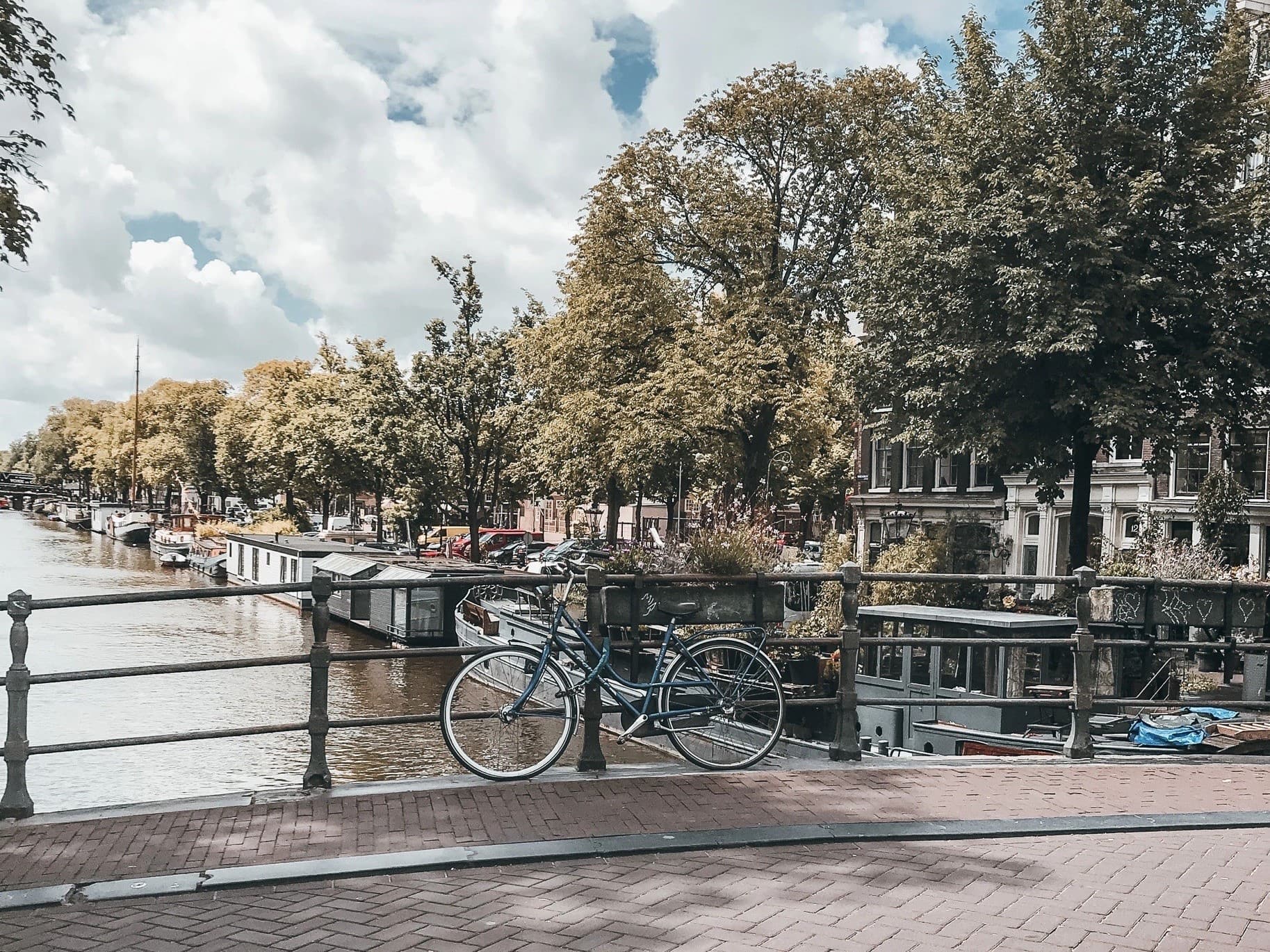 Vegane Städte: Blick von einer Brücke in Amsterdam auf eine Gracht, auf der Brücke ein Fahrrad.