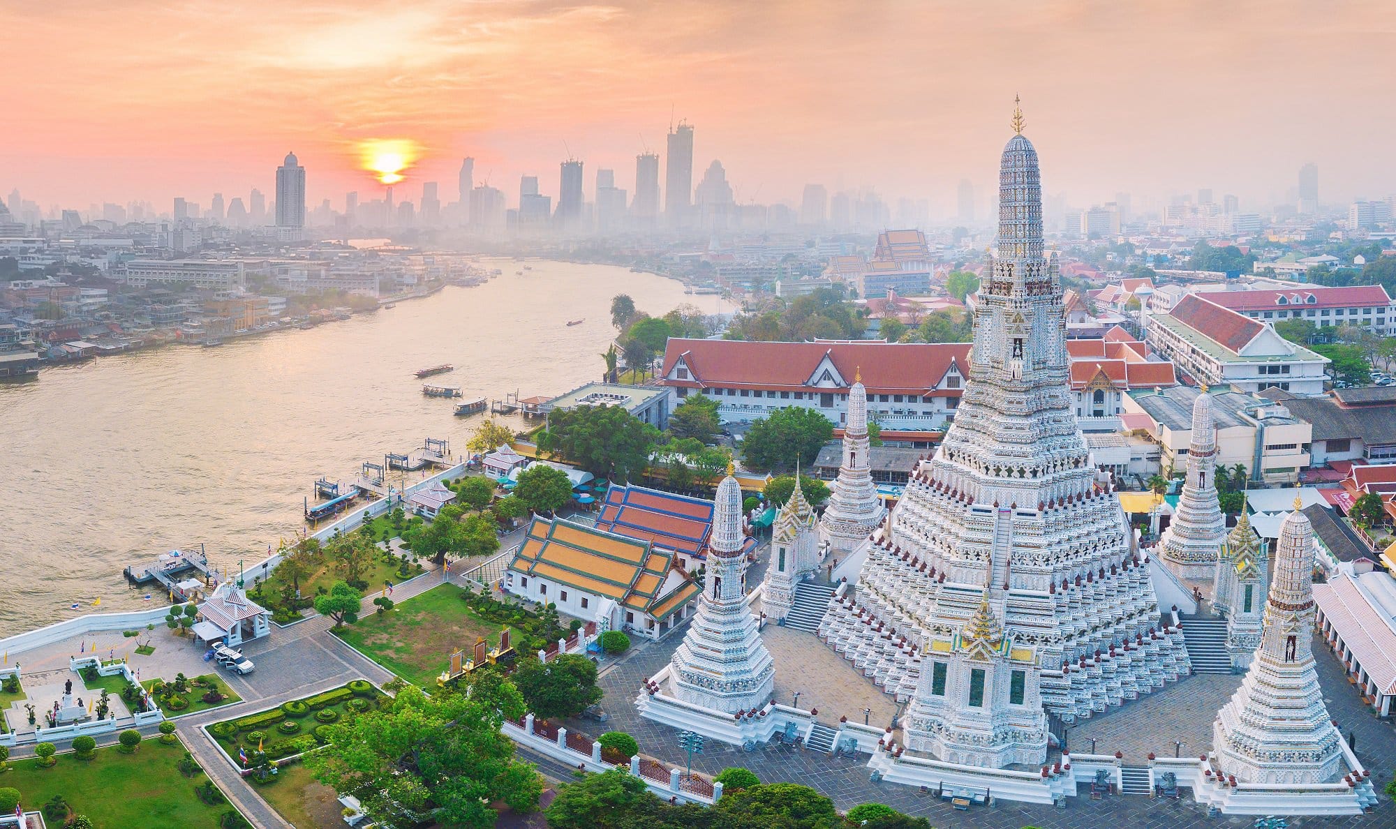 Vegane Städte: Blick auf Bangkoks Skyline am Fluss mit Wat Arun im Vordergrund, bei untergehender Sonne.
