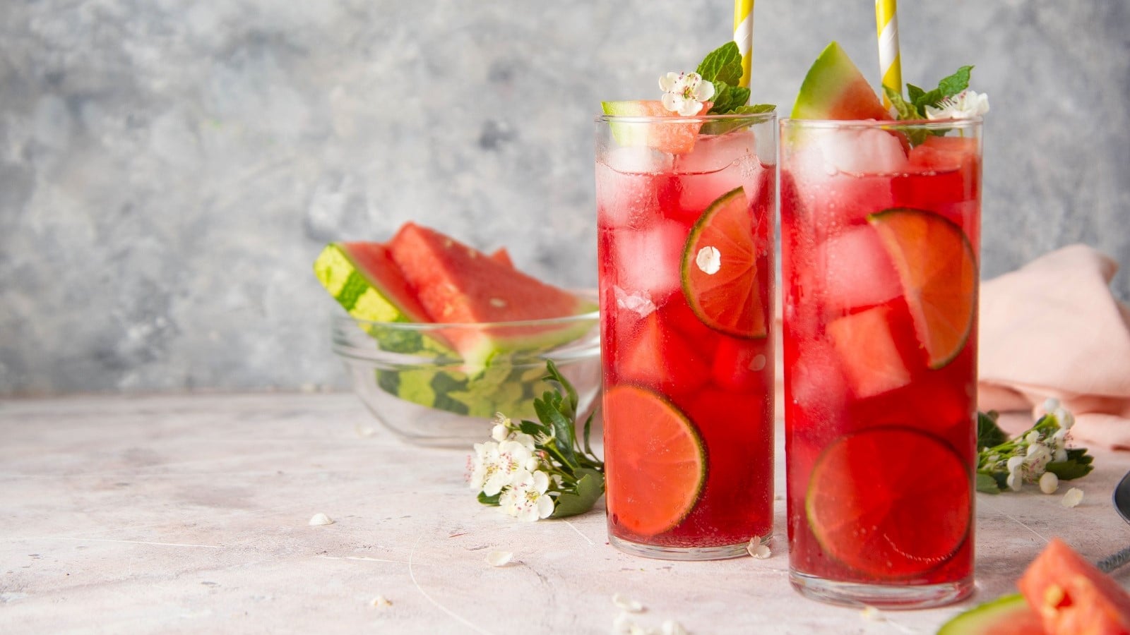 Zwei Gläser mit Wassermelonen-Limonade vor einem grauen Hintergrund.