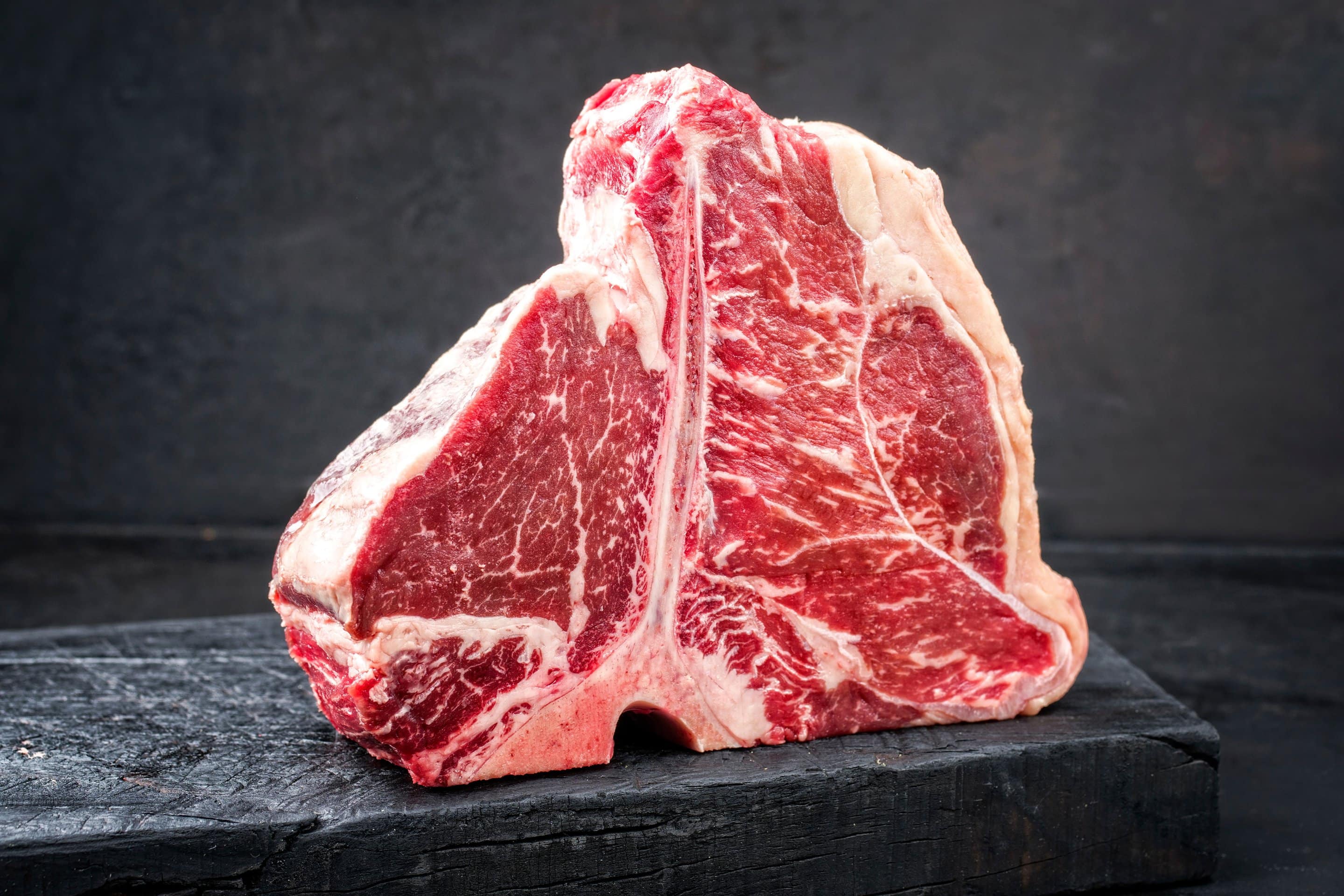Aufrecht stehendes Porterhous-Steak auf schwarzer Schieferplatte. Frontalansicht.