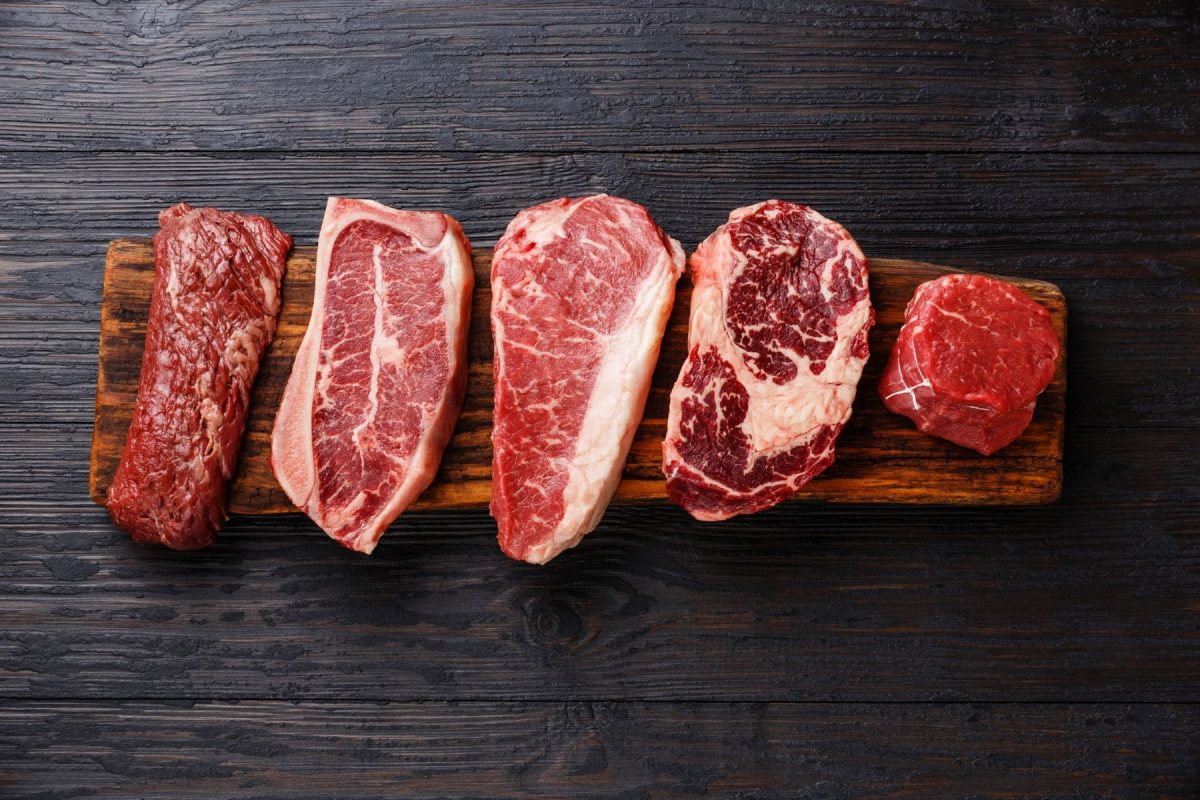 Welche Steaksorten gibt es verschiedene Steaks auf Holz und schwarzem Untergrund. Draufsicht.