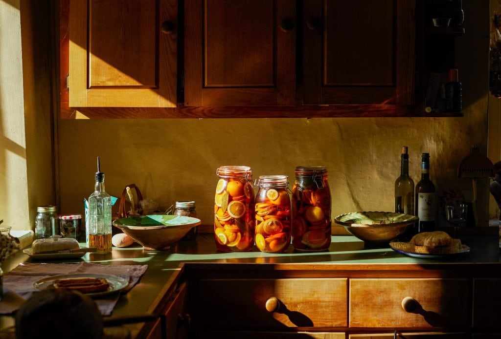 Einblick in die gemütliche Küche auf dem Land mit eingeweckten Orangen auf dem Tisch.