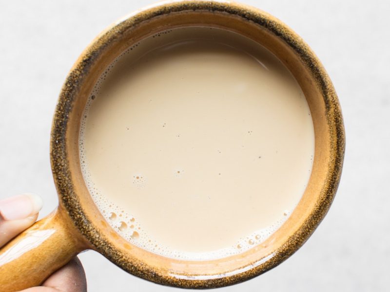 Evaporated milk bzw. Kondensmilch in einer braunen Keramiktasse aus der Vogelperspektive.