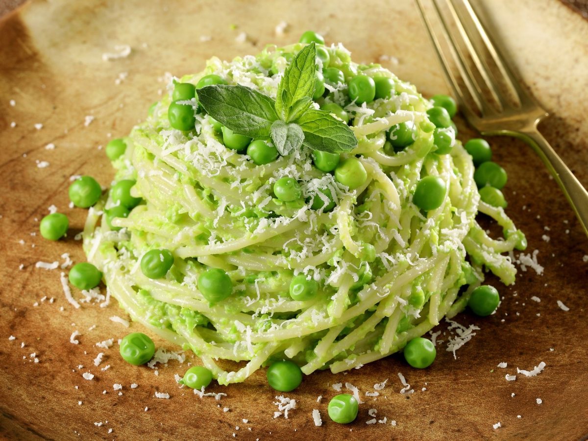 Draufsicht, schräg: Ein Teller Pasta e piselli. Neben dem Erbsen-Gericht für Gartenbesitzer liegt eine Gabel.