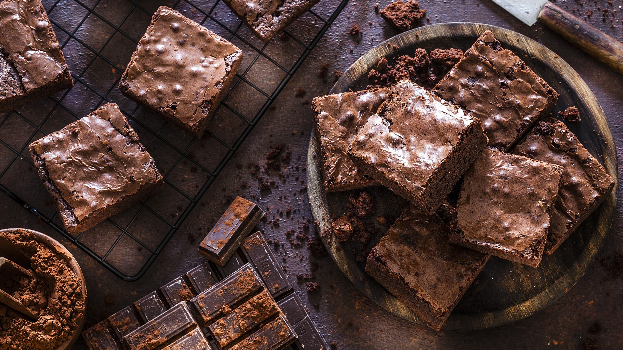 Frisch gebackene Brownies in Nahaufnahme mit sichtbaren Schokoladenstückchen und Kakao bestäubt.