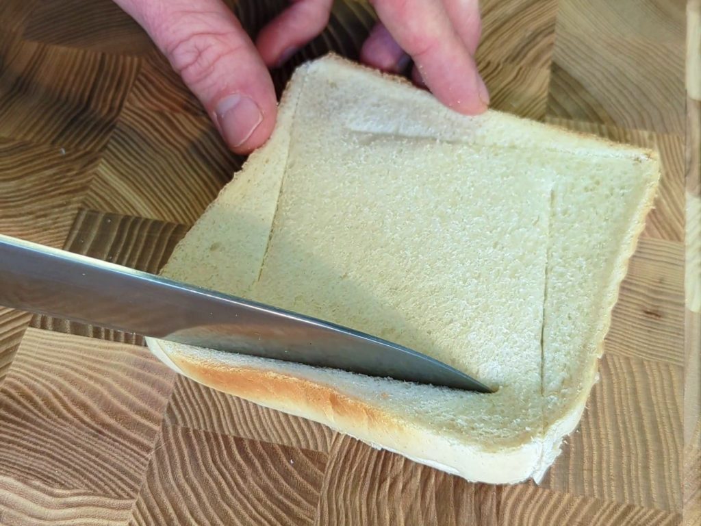 Ein angeschnittenes Toast mit Messer auf einem Schneidebrett.